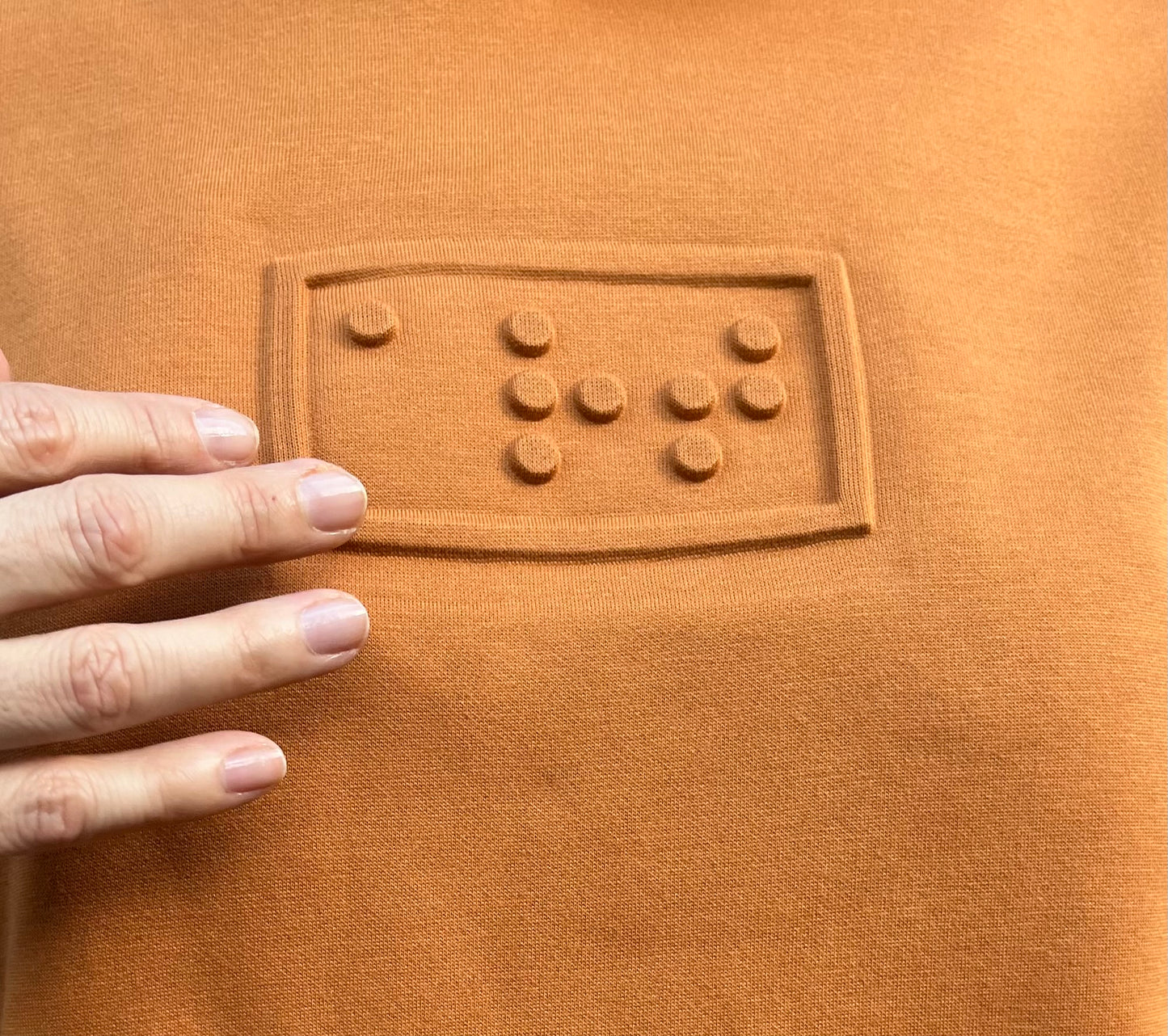 art embossé en braille sur un hoodie ocre