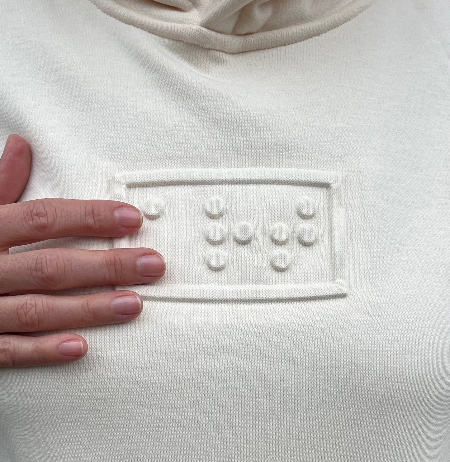 art embossé en braille sur un hoodie sable